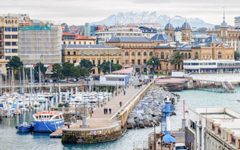 San Sebastian harbor view with historic buildings and marina, part of self-guided city exploration game.