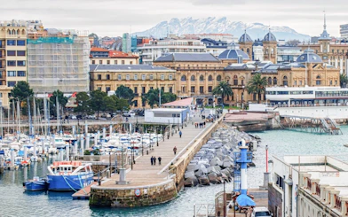San Sebastian harbor view with historic buildings and marina, part of self-guided city exploration game.