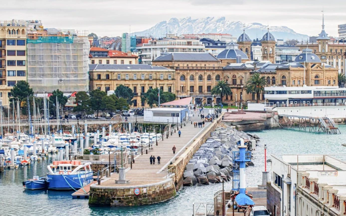 San Sebastian harbor view with historic buildings and marina, part of self-guided city exploration game.