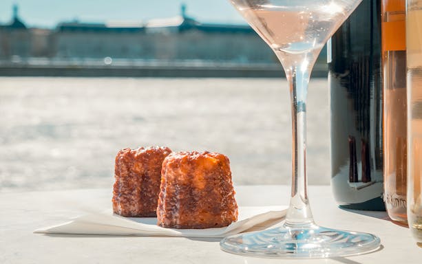 Canelés and wine glass on Bordeaux River Cruise table.