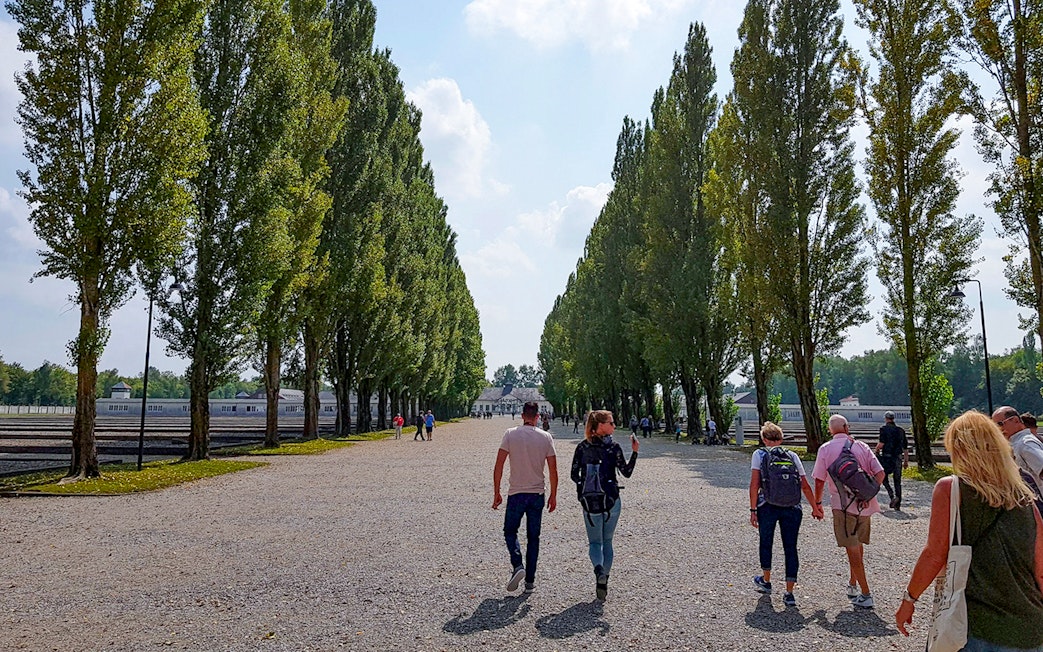 Visitors walking along tree-lined path at Dachau Concentration Camp, Germany.
