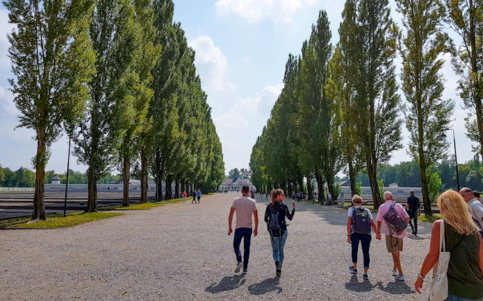 Visitors walking along tree-lined path at Dachau Concentration Camp, Germany.