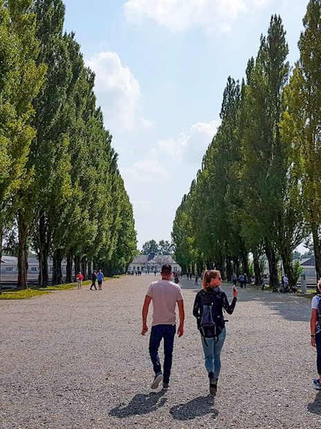 Visitors walking along tree-lined path at Dachau Concentration Camp, Germany.