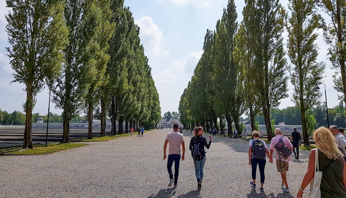 Visitors walking through Dachau Concentration Camp grounds, Germany, exploring historical site.