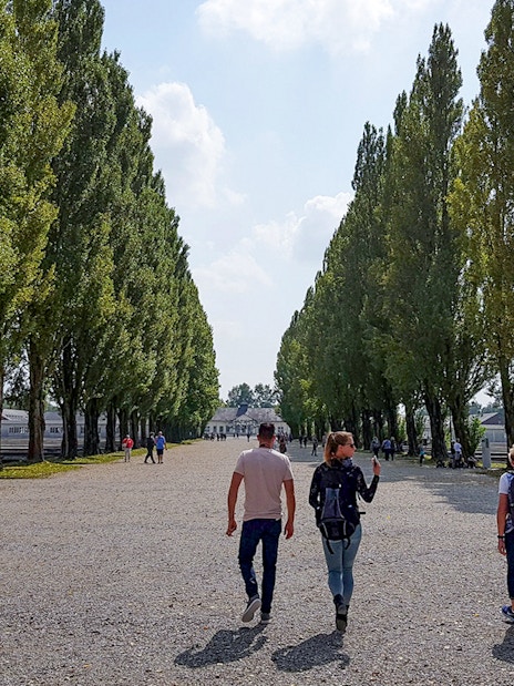 Visitors walking along tree-lined path at Dachau Concentration Camp, Germany.