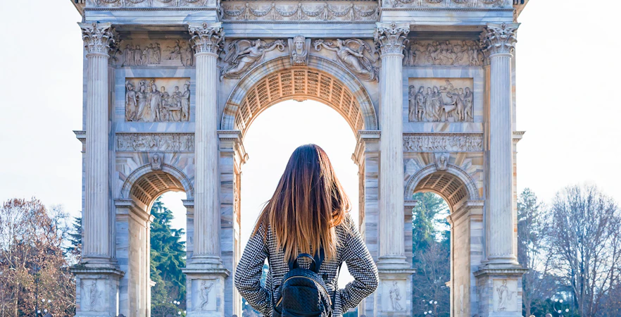 Person standing in front of the Arc de Triomphe in Paris, France.