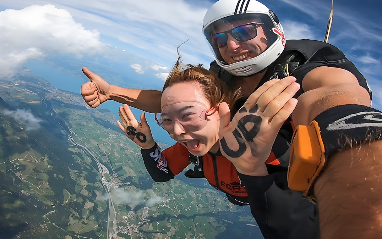 Tandem skydive over Swiss landscape from 13,000 ft, smiling participants.