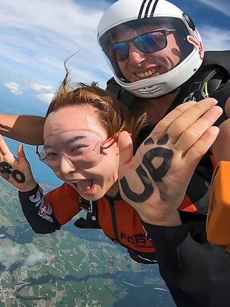 Tandem skydive over Swiss landscape from 13,000 ft, smiling participants.