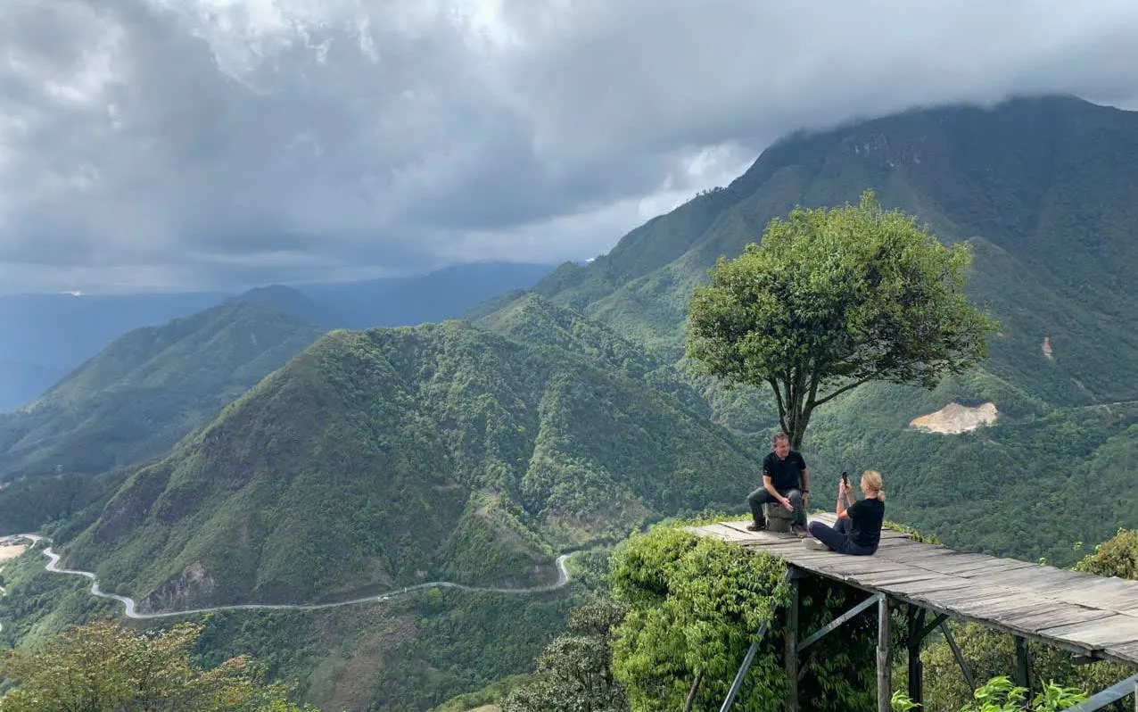 Mountain view in Sapa with two people on a wooden platform, part of a customizable motorbike tour.