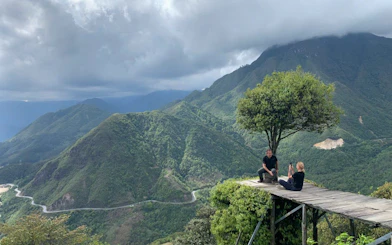 Mountain view in Sapa with two people on a wooden platform, part of a customizable motorbike tour.