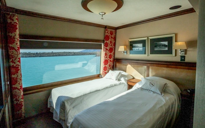 Deluxe room with twin beds and lake view on Spirit of the Glaciers tour boat.