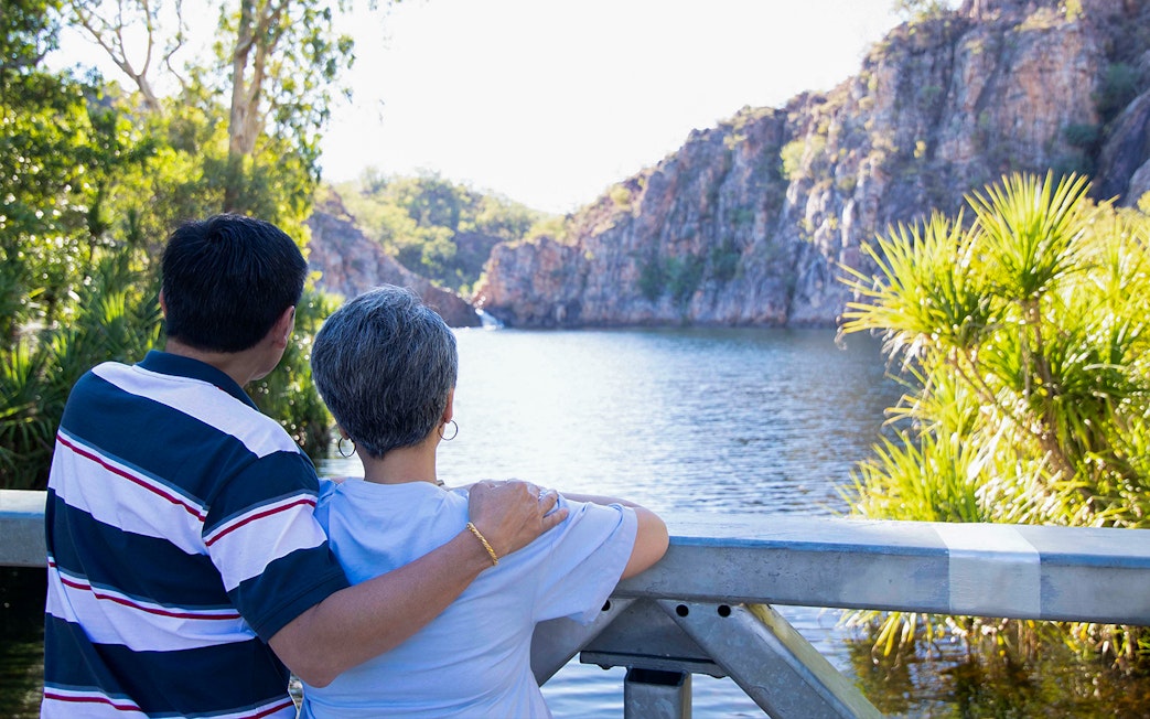 Couple enjoying view of Katherine Gorge from a lookout, surrounded by lush greenery.