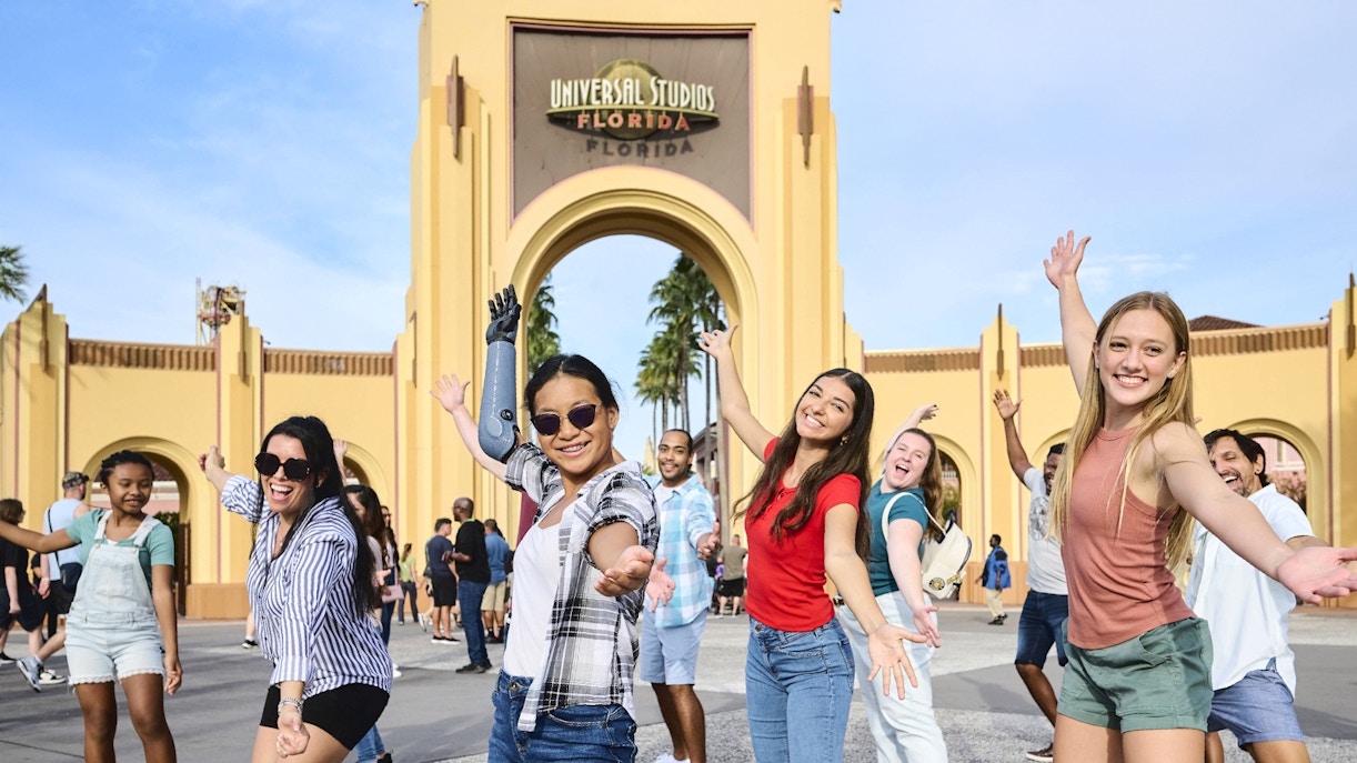 Guests smiling in front of Universal Studios entrance arch, Orlando.