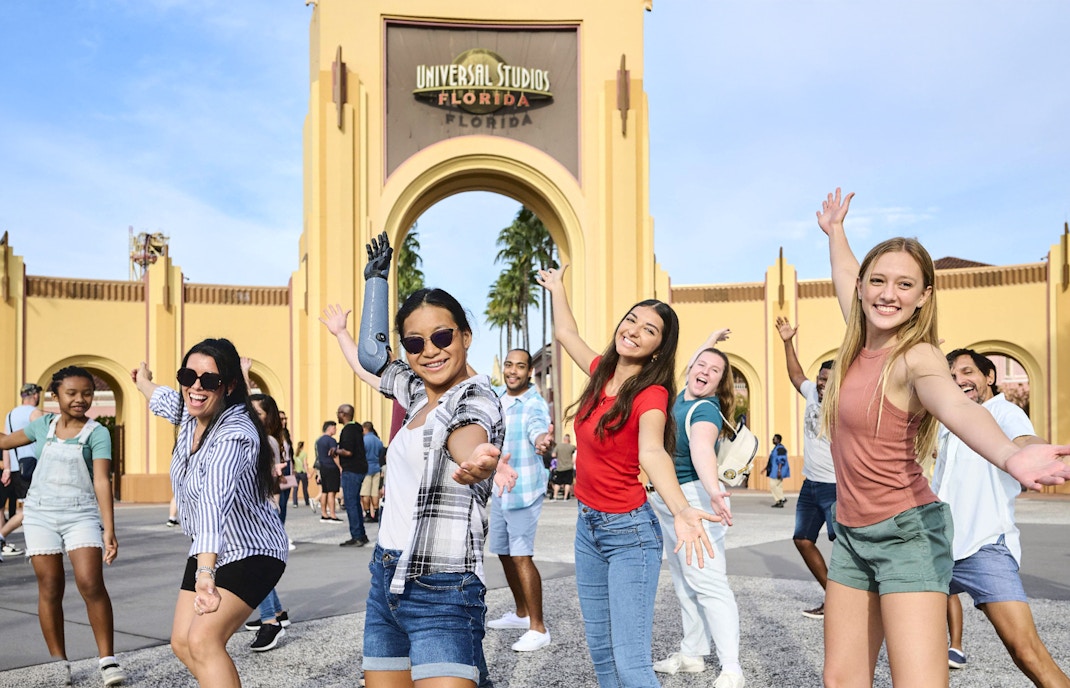Guests posing at Universal Studios entrance arch, Universal Studios Resort, Orlando.