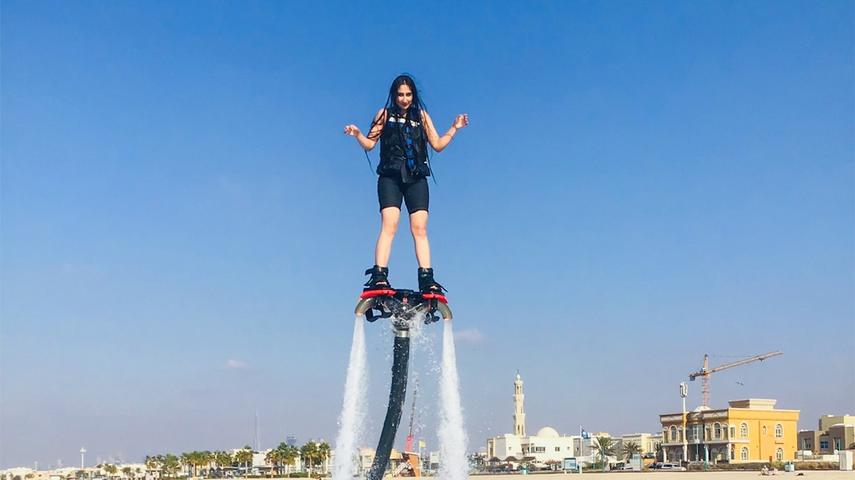 Flyboarding over water with Dubai skyline in the background.