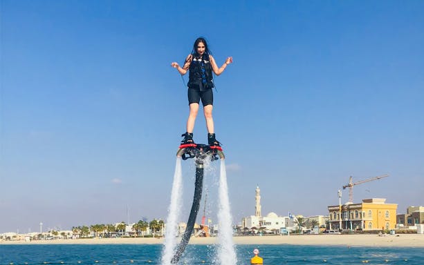 Flyboarding over water with Dubai skyline in the background.