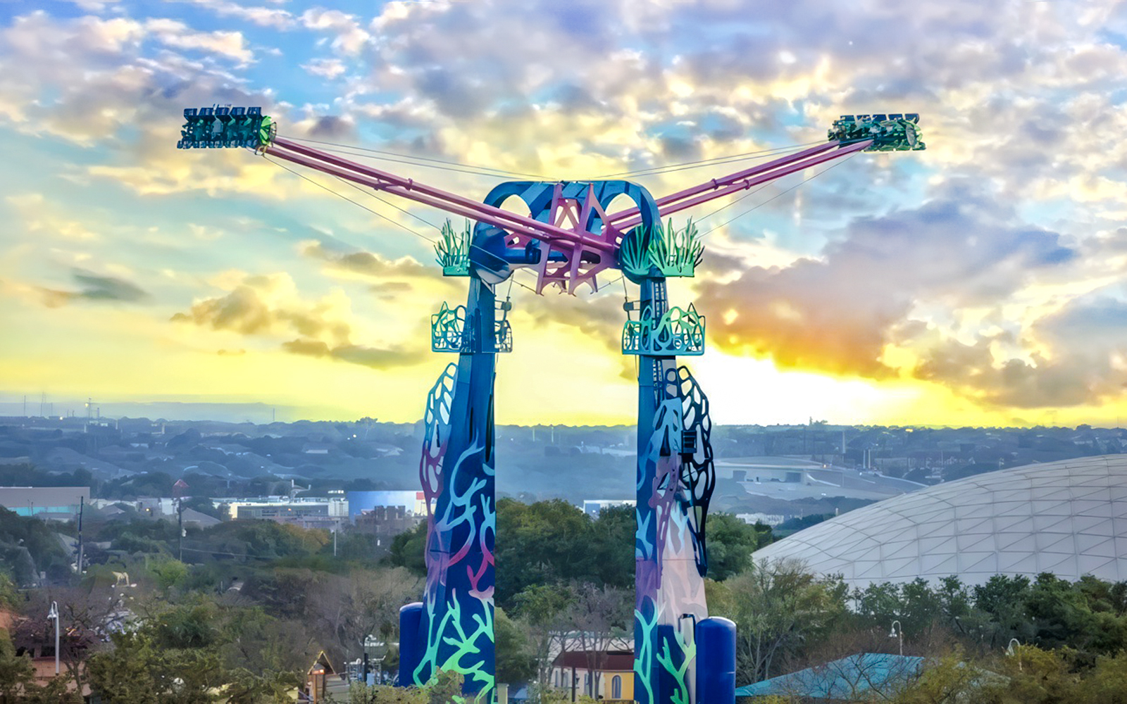SeaWorld San Antonio ride with colorful towers and sunset backdrop.