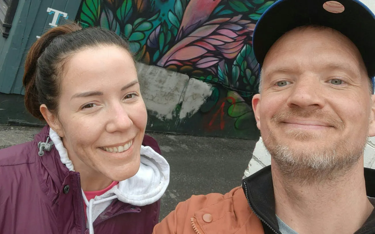 Colorful street art mural in Ottawa with two people smiling in front.
