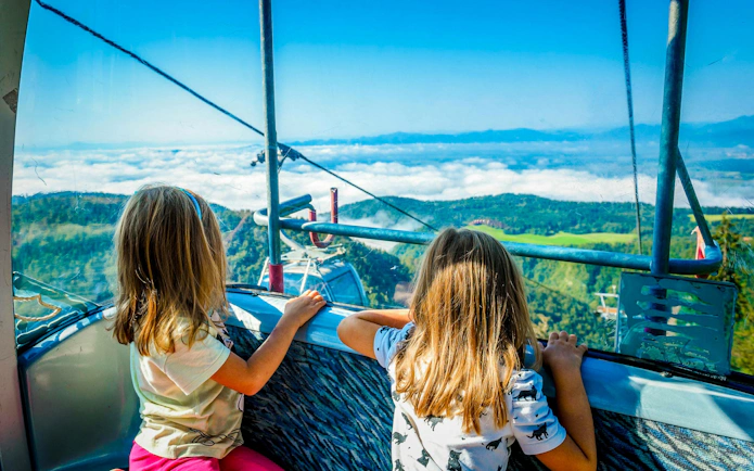 Twin girls in cable car overlooking scenic landscape near Palace of Holyroodhouse.