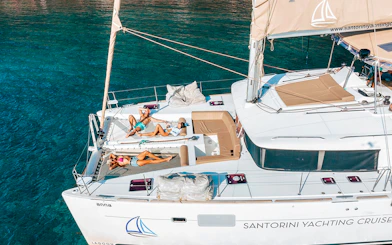 Catamaran with people sunbathing on deck, Santorini Luxury Cruise.