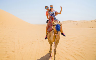 Camel ride in the desert with two people enjoying the experience.