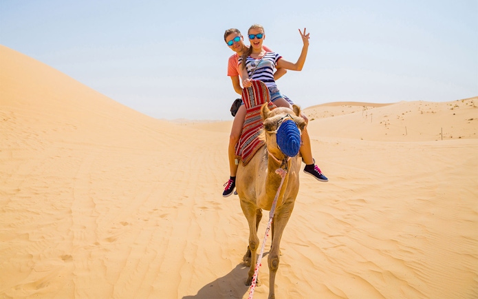 Camel ride in the desert with two people enjoying the experience.