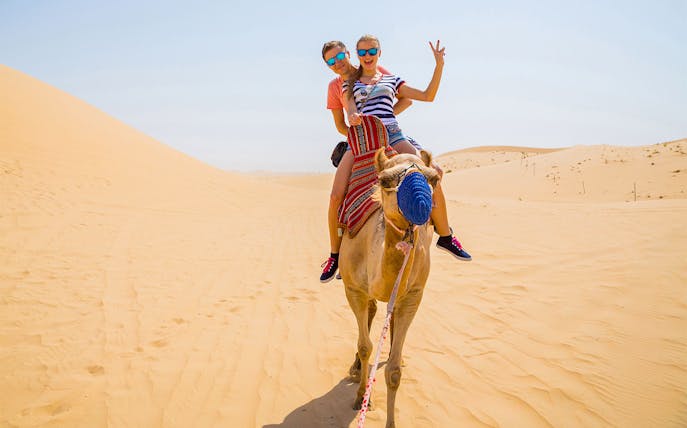 Camel ride in the desert with two people enjoying the experience.