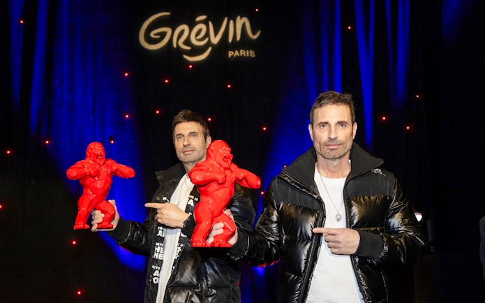 Two men holding red gorilla sculptures at Grévin Paris, related to Richard Orlinski wax figure.