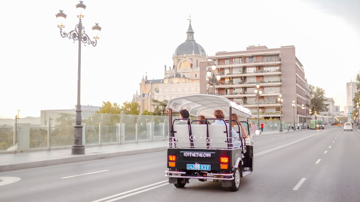 Electric tuk-tuk driving near Almudena Cathedral in Madrid, Spain.