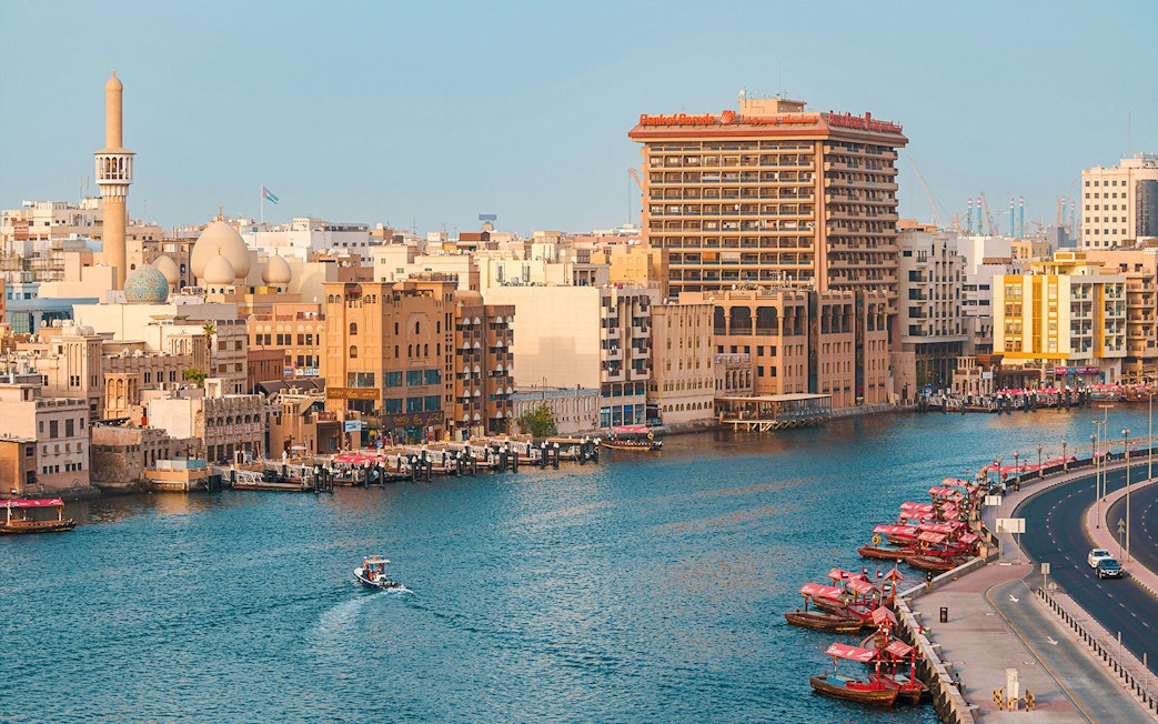 Dubai Creek with traditional boats and city skyline in the background.