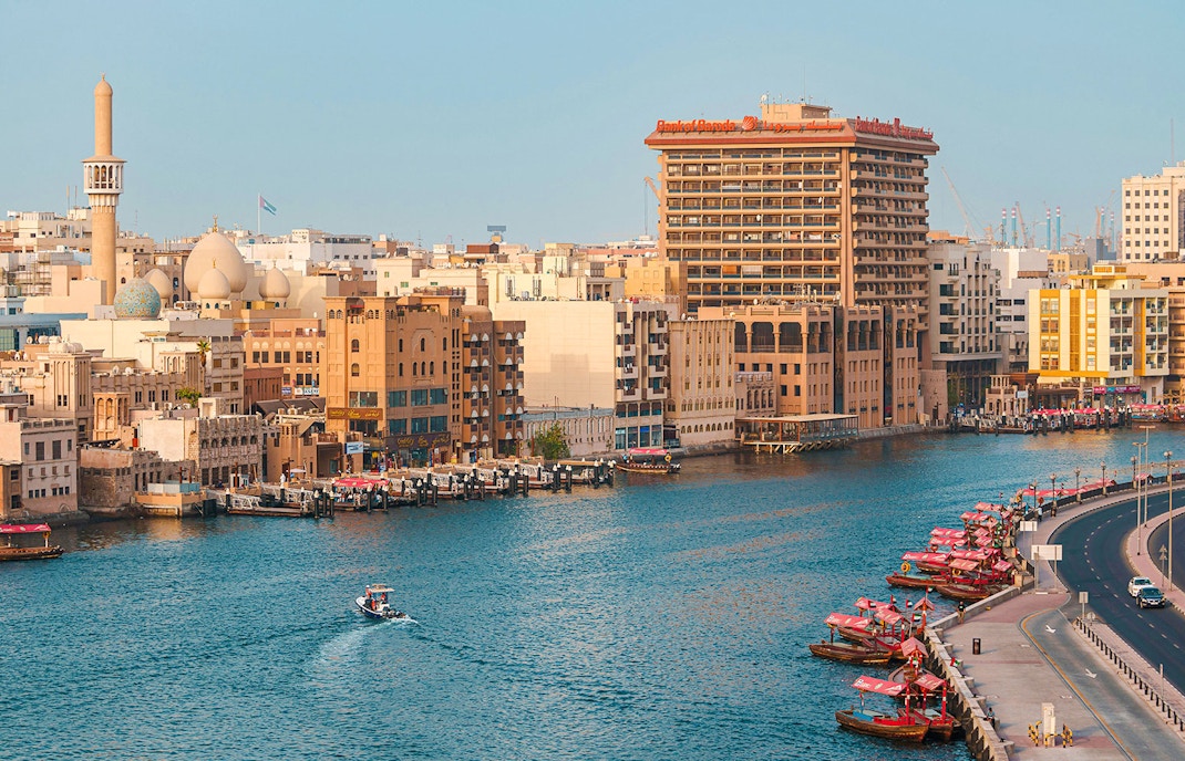 Dubai Creek with traditional boats and city skyline in the background.