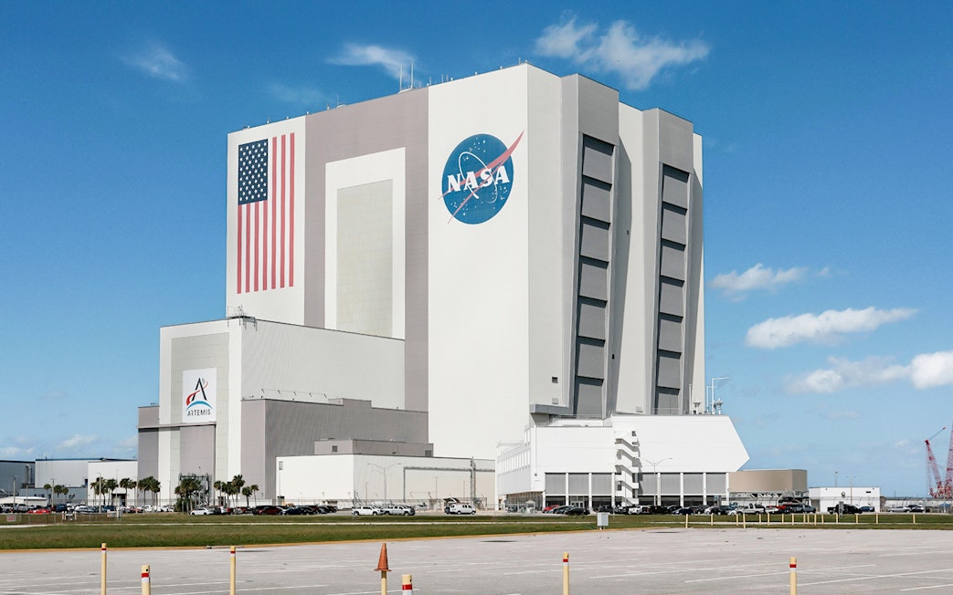 NASA Kennedy Space Center Vehicle Assembly Building with American flag and logo.
