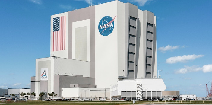 NASA Kennedy Space Center Vehicle Assembly Building with American flag and logo.