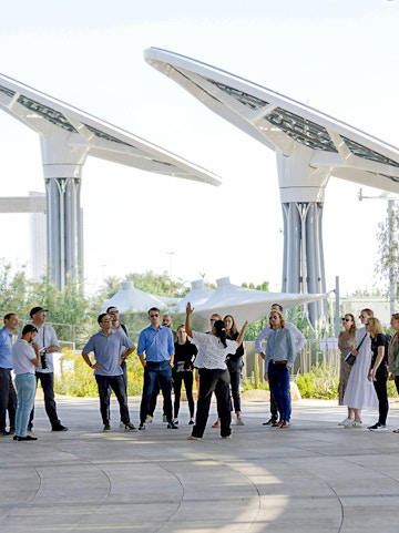 Guide engaging with tourists at Expo City Dubai pavilion.