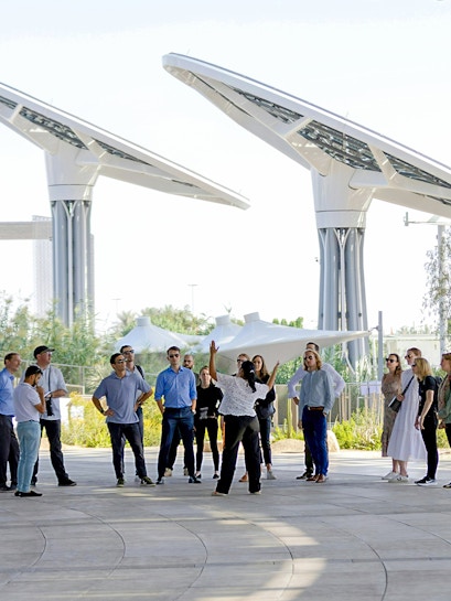 Guide engaging with tourists at Expo City Dubai pavilion.