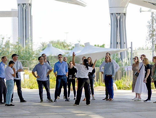 Guide engaging with tourists at Expo City Dubai pavilion.