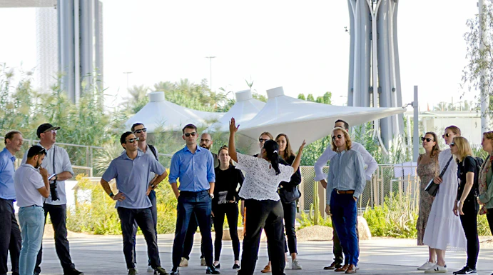 Guide engaging with tourists at Expo City Dubai pavilion.