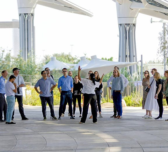 Guide engaging with tourists at Expo City Dubai pavilion.
