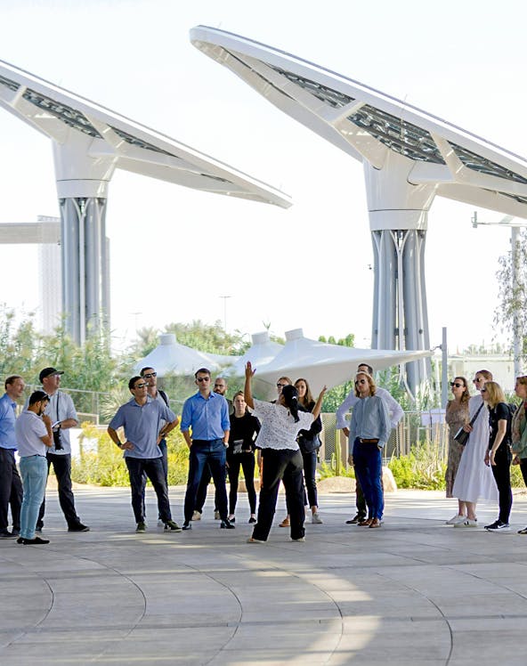 Guide engaging with tourists at Expo City Dubai pavilion.
