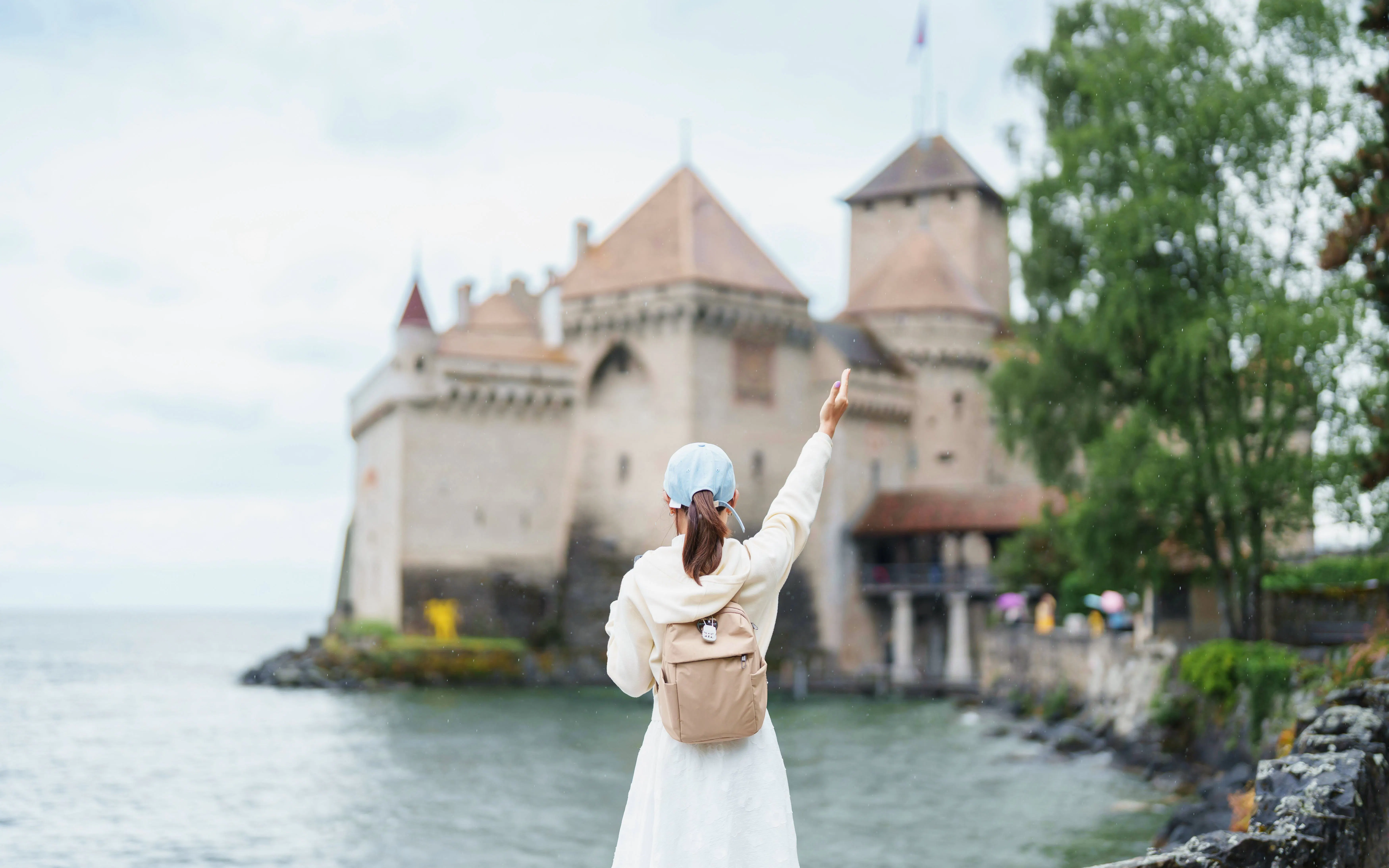 Tourist pointing at Chillon Castle on Lake Geneva, Montreux, Switzerland in summer.