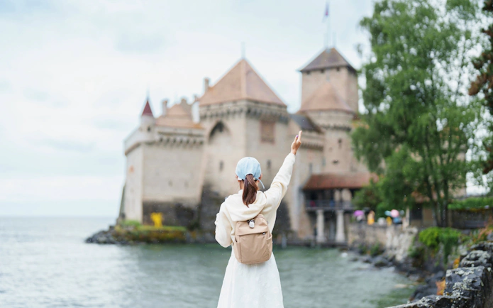 Tourist pointing at Chillon Castle on Lake Geneva, Montreux, Switzerland in summer.