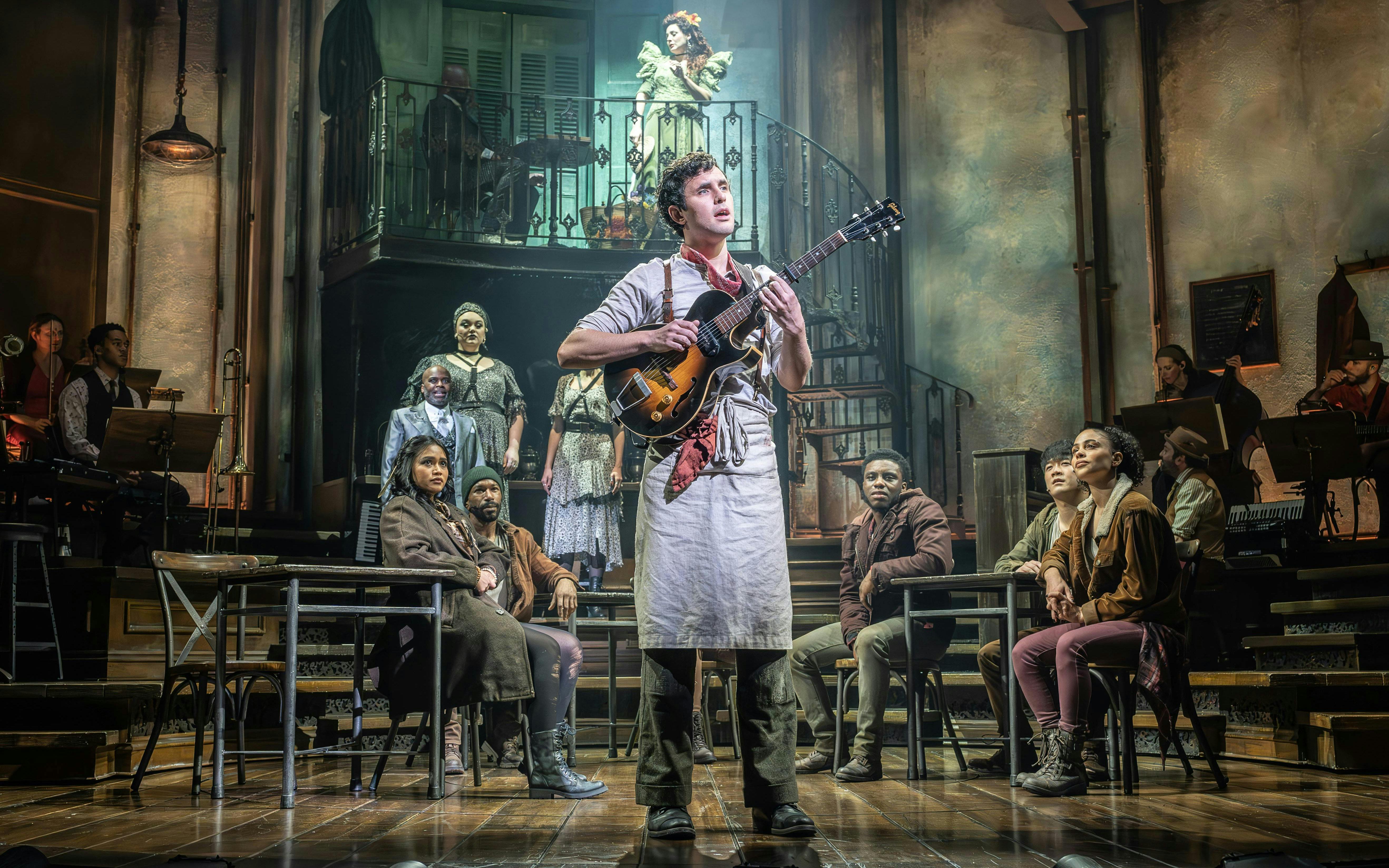 Performer with guitar on stage during Hadestown show, West End.