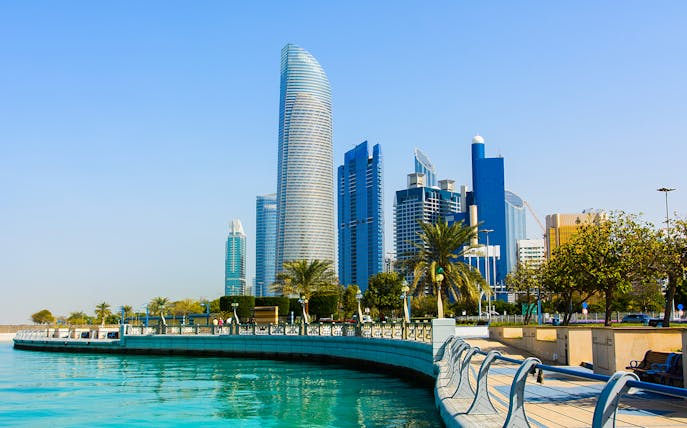 Abu Dhabi Corniche with modern skyscrapers and waterfront promenade.