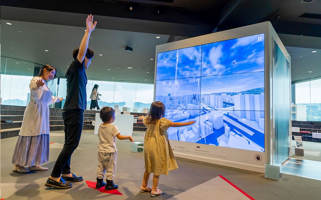 Visitors interacting with a digital display at Hiroshima Orizuru Tower.