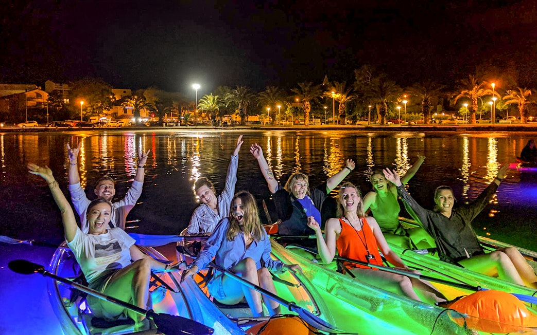 Group enjoying a nighttime SUP Glow Tour in Split with illuminated kayaks.
