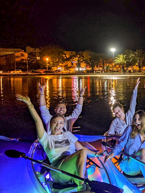 Group enjoying a nighttime SUP Glow Tour in Split with illuminated kayaks.