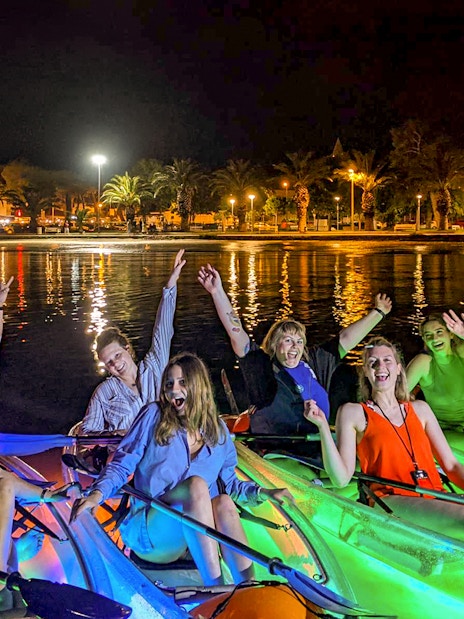 Group enjoying a nighttime SUP Glow Tour in Split with illuminated kayaks.