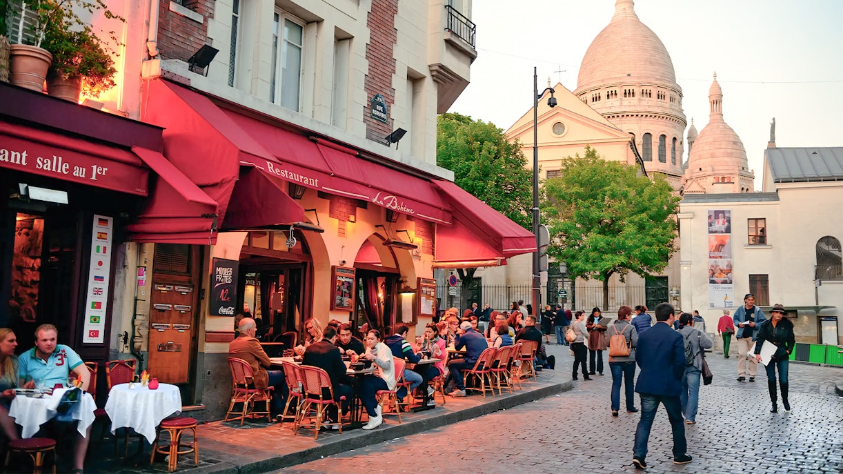Montmartre Paris restaurant exterior with outdoor seating and vibrant street art.
