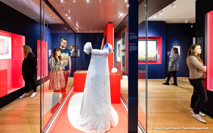 Visitors viewing a historical dress exhibit at Kensington Palace's Untold Lives tour.