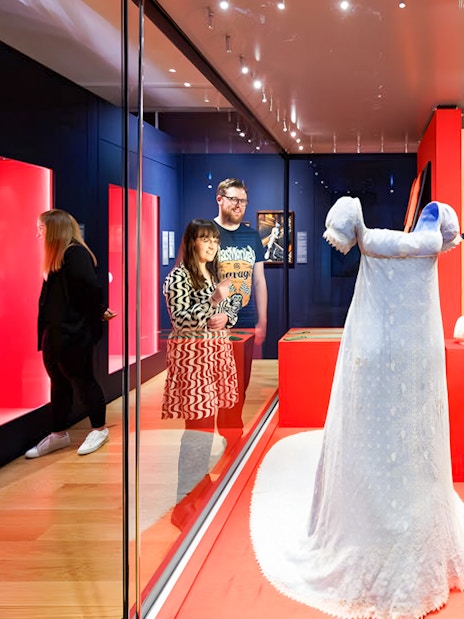 Visitors viewing a historical dress exhibit at Kensington Palace's Untold Lives tour.